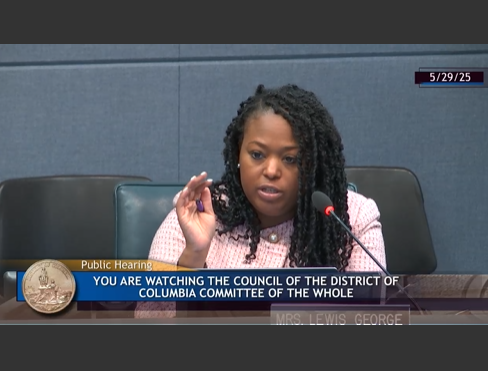 Photo of CM Janeese Lewis George on the dais at the Committee of the Whole hearing on May 29, 2025. She is wearing a pink checkered suit with pearl buttons.